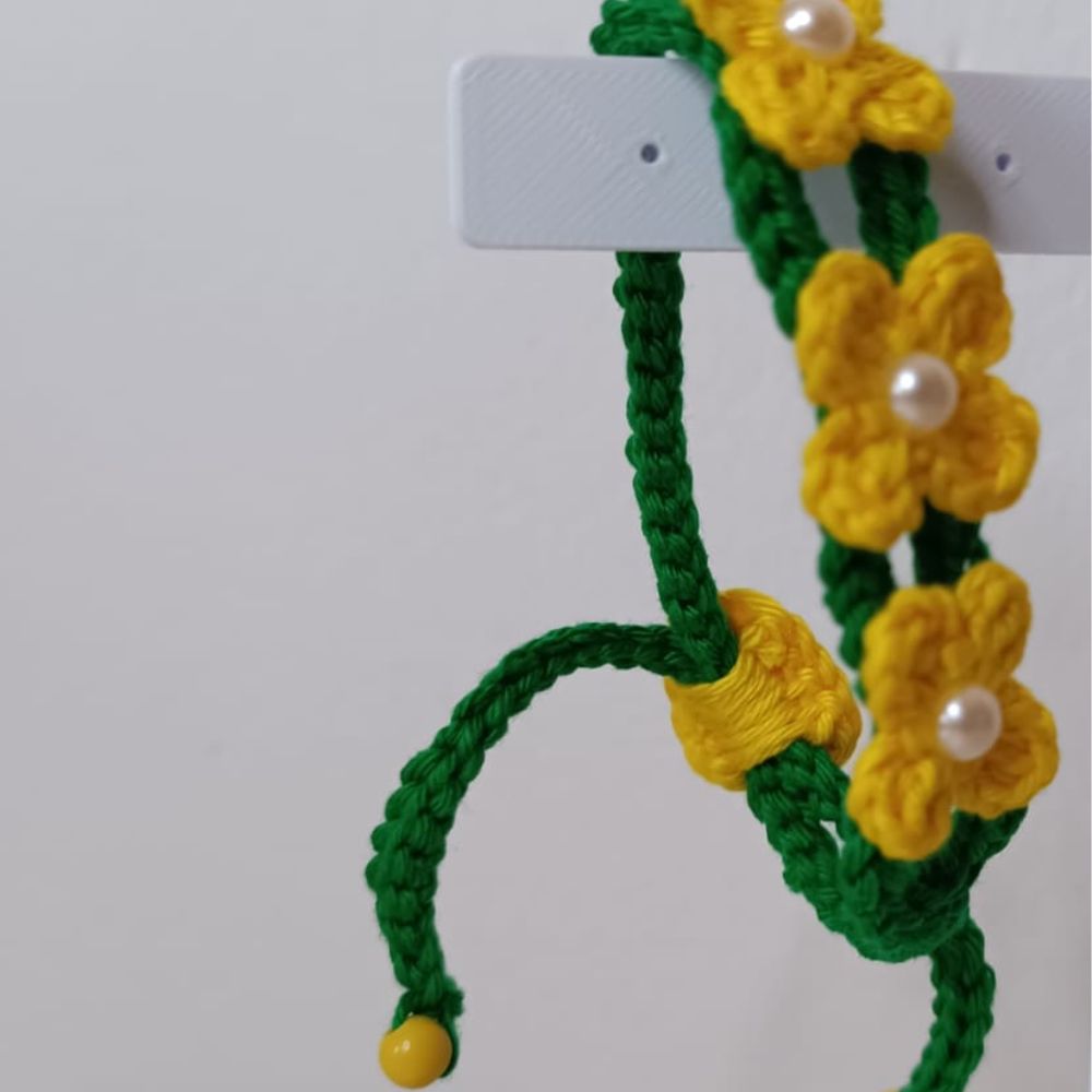 Pulseira Brasil em Flor em Crochê Artesanal 4 Pulseira Brasil em Flor em crochê artesanal nas cores verde e amarelo, com flores delicadas e detalhes em pérolas.