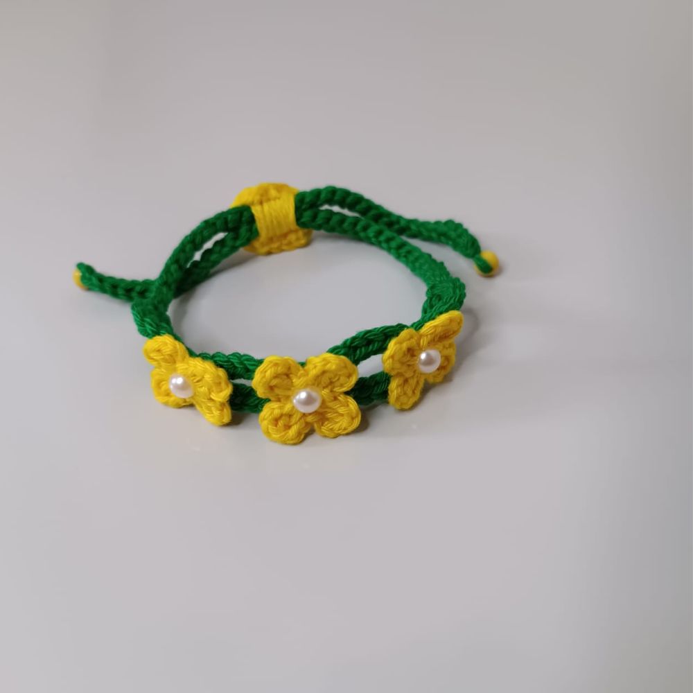 Pulseira Brasil em Flor em Crochê Artesanal 2 Pulseira Brasil em Flor em crochê artesanal nas cores verde e amarelo, com flores delicadas e detalhes em pérolas.